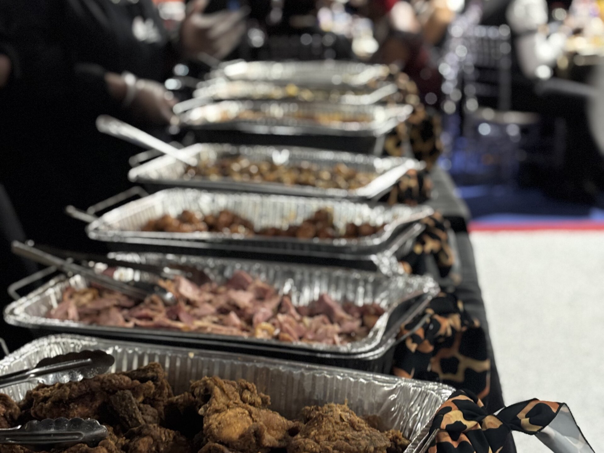 Chafing dishes lined up with meatballs, chicken, and smoked meats